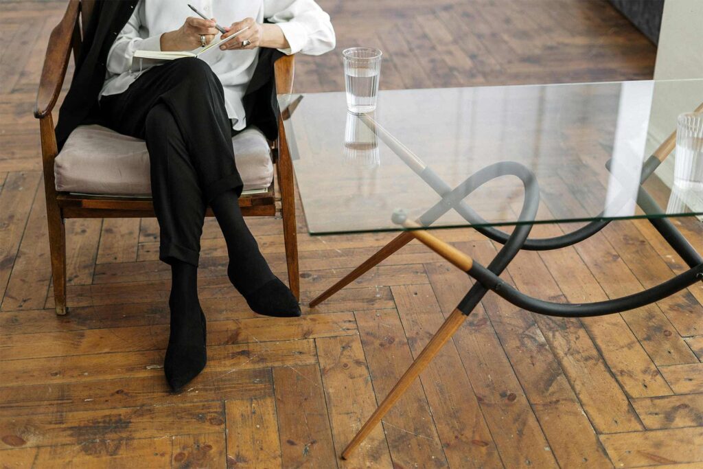Woman sitting in chair with a notepad by a table with a glass of water